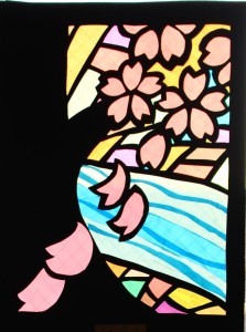 川辺に咲く桜の木と、花びらが散る様子が描かれたステンドグラスの作品の写真