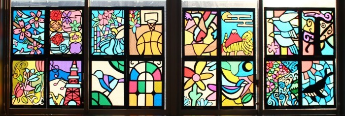 花や、動物、観光名所などが描かれたステンドグラスの作品が1枚の窓に4枚飾られ、計16枚並んでいる写真