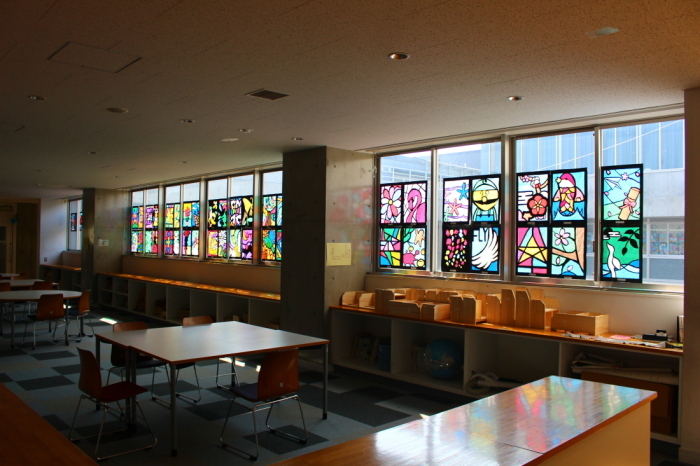 薄暗い教室の窓に飾られたステンドグラスの作品に、太陽の光がさしている写真