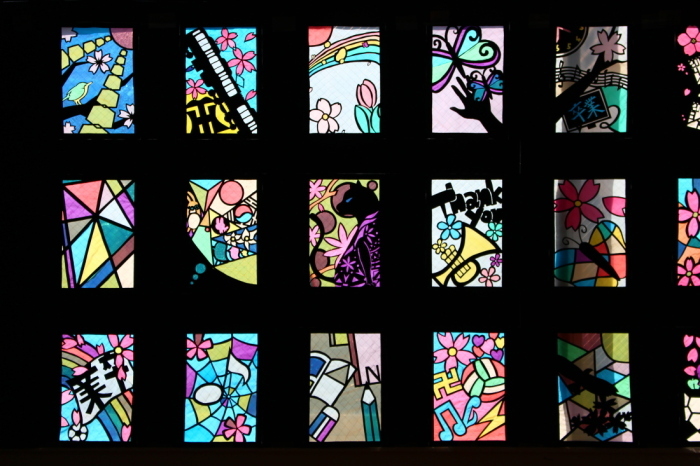 幾何学模様や、虹と花、蝶などがなどが描かれたステンドグラスの作品の写真