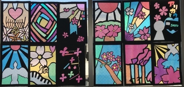 桜の木や、白い鳥、花びらなどが描かれたステンドグラスの作品が並んでいる写真