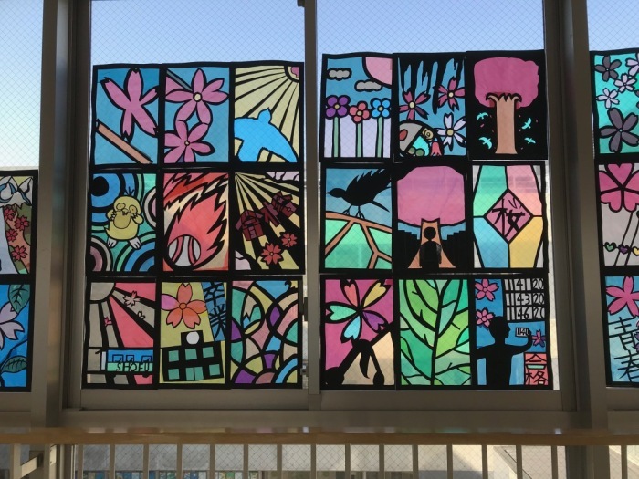 鳥や、桜の木、木花などが描かれたステンドグラスの作品が窓に飾られている写真