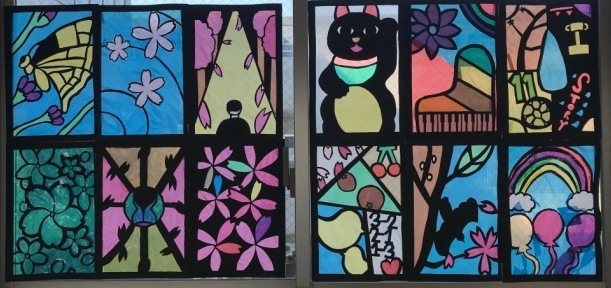 黒い猫、蝶や虹と風船などが描かれたステンドグラスの作品の写真