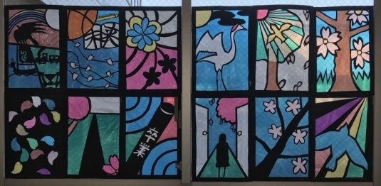 鶴や、カラフルな花びら、ボールや女の子などが描かれたステンドグラスの作品の写真