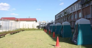 校舎の左側の屋外に5つのテントが設置された北グラウンド横防災スペースの写真