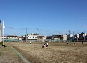 生徒たちが走ったり練習を行っている大きなネットに囲まれたグラウンドの写真