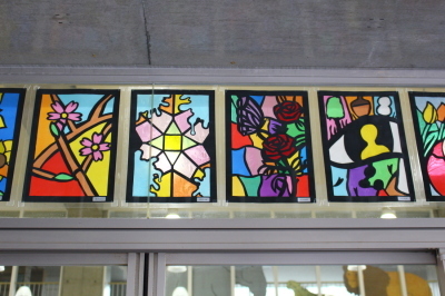 桜の木の枝、バラの花、目の中に写る黄色い人などが描かれた4枚のステンドグラスの作品の写真