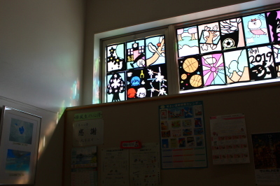 窓に飾られたステンドグラスの作品に、太陽の光がさし、薄暗い室内にカラフルな光のラインを作っている写真