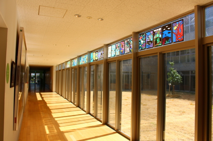 校長室前廊下の上の窓の方にステンドグラスの作品が飾られている写真