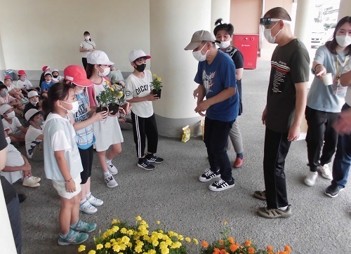 花の苗を頂いた社会福祉法人『桜の園』の方と4名の児童が向かい合いお礼の言葉を伝えている写真