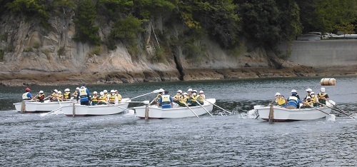 児童たちが4艘の白色のボートに乗り川を漕いでいる写真