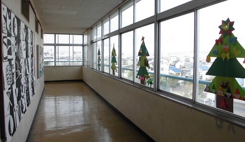 廊下の窓ガラスに大きなクリスマスツリーが飾られている写真