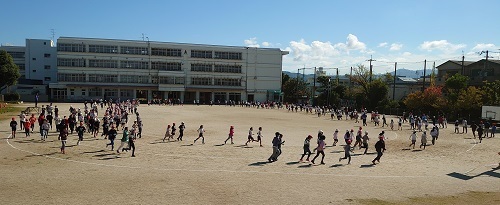 校庭を児童たちが走っているマラソンタイムの様子の写真