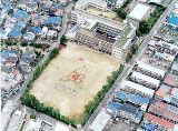 人文字で大きく校章が作られた運動場が見える藤田小学校をアップで写した航空写真