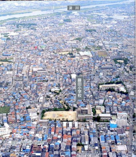 写真の上部に淀川が流れ、藤田小学校が中央に見える2000年6月の空撮写真