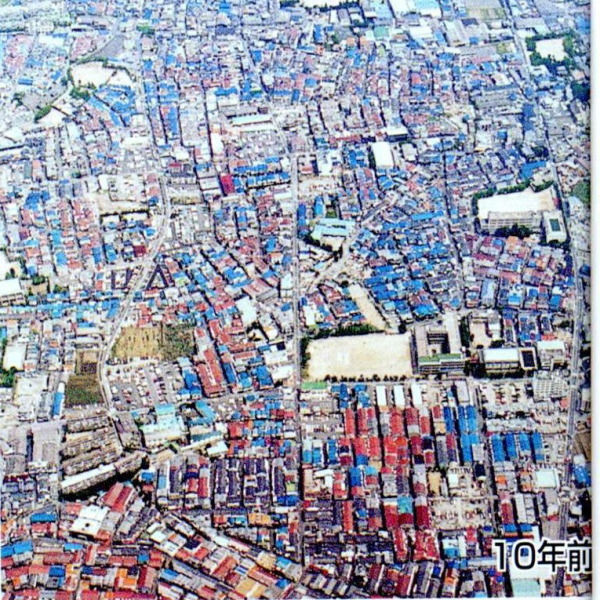真ん中に道路があり、屋根が赤と青の家がたくさん点在している1990年ごろの空撮写真