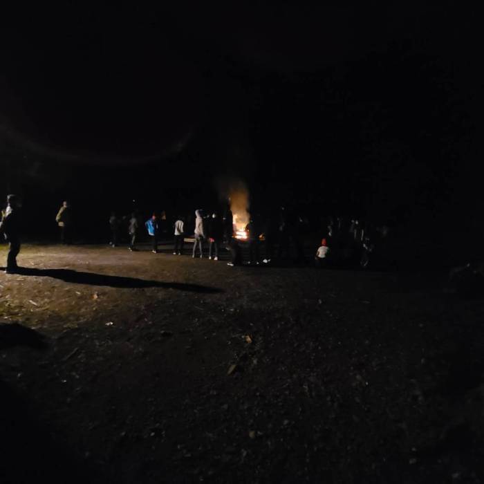 真っ暗な夜空の下、生徒たちがキャンプファイヤーをしている写真
