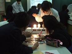 班に分かれた金田小学校の児童が、手回し発電機を回して電球を点灯させている様子を写した写真