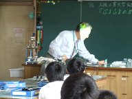 大阪工業大学の先生が、不思議な物体を立てておいておくところを守口小学校の児童が見ている様子を写した写真