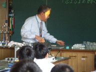 大阪工業大学の先生が、不思議な物体が時間が経つと平らになるところを守口小学校の児童に示している様子を写した写真