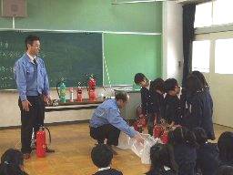 橋波小学校の児童が、講師の監督のもと訓練用の水消火器を体験している様子を写した写真