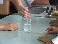 守口小学校の児童が、水道水に粉を入れるという実験を行っている様子を至近距離で写した写真