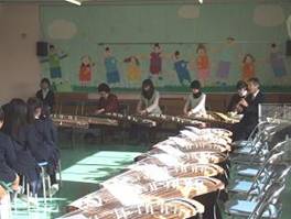 滝井小学校の児童が、大阪音楽大学の中島名誉教授、尺八の塚本氏による「春の海」等の演奏を鑑賞している様子を写した写真