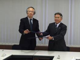 左に井上学長、右に藤川教育長が協定書を交換する様子を写した写真