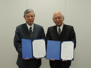 左に首藤教育長、右に山崎学長が協定書を持って立っている様子を写した写真