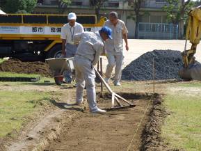 芝生化区画の中央にレンガの小道を作るため、作業員らが小道の部分の土を掘っている姿を写した写真