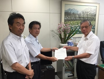 絵画が飾られている室内で、坂田副会長が左側に立ち、中谷会長から提言書を受け取っている首藤教育長の写真