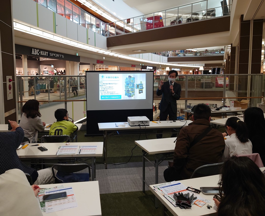 以前のケータイ分解教室の様子(講義する男性と聞く親子の皆さん)