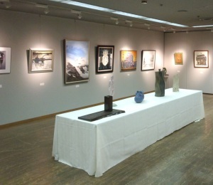 中央のテーブルに花瓶、壁には絵画が展示されている写真