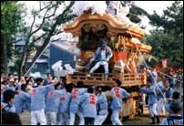 神輿の中央に1人の男性が乗り、たくさんの人が神輿を担いている八雲神社祭礼山車の写真