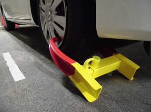 自動車のタイヤに赤と黄色二色のタイヤロックがかけられている様子