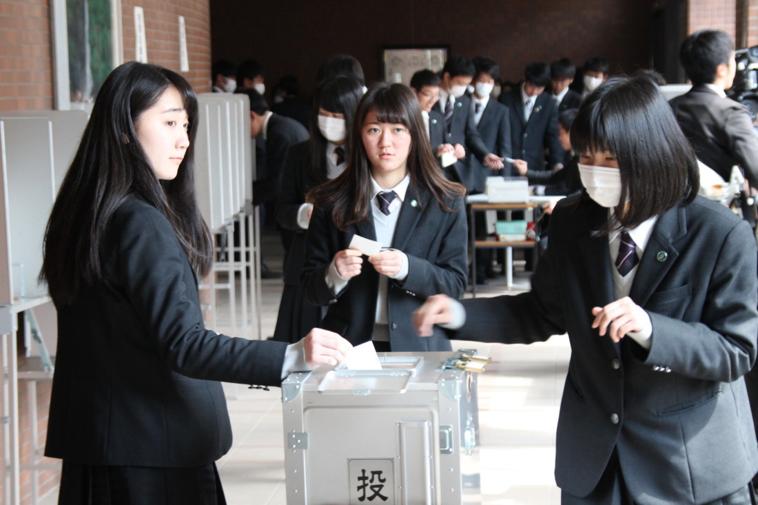 投票箱に投票している女子学生の写真