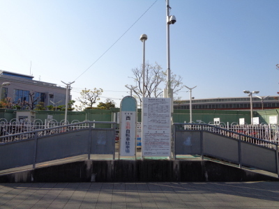 中央に大日駅西有料自転車駐車場と書かれた看板と、注意書きが記された看板が立っている大日駅西自転車駐車場を正面から写した写真