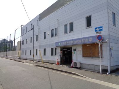 白い建物の出入り口に青く太子橋今市駅自転車駐車場と記された、太子橋今市駅自転車駐車場を斜め右から写した写真