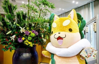 生けられたお花の横でもり吉が年賀状を持っている写真
