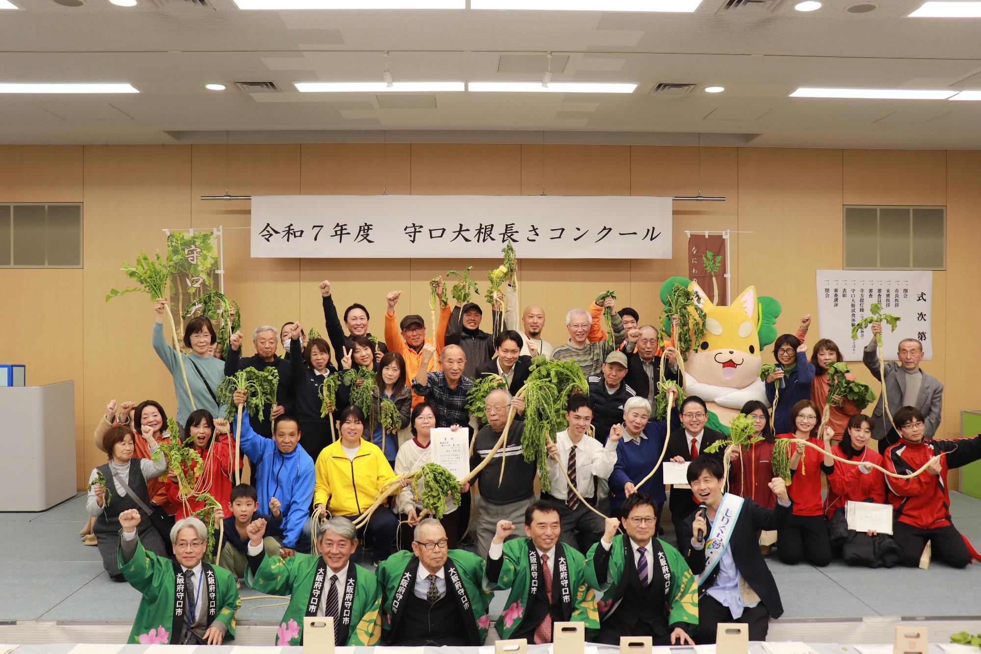 令和7年度守口大根長さコンクールでみんなが集まって守口大根を掲げて集まっている様子