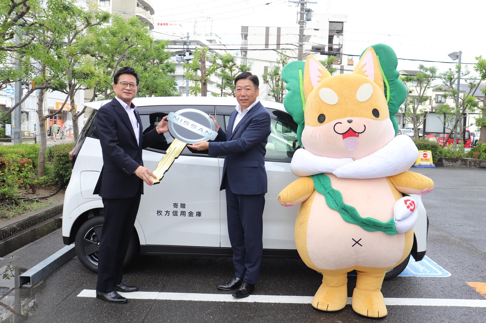 日産サクラの前で鍵の贈呈式を見守るもり吉