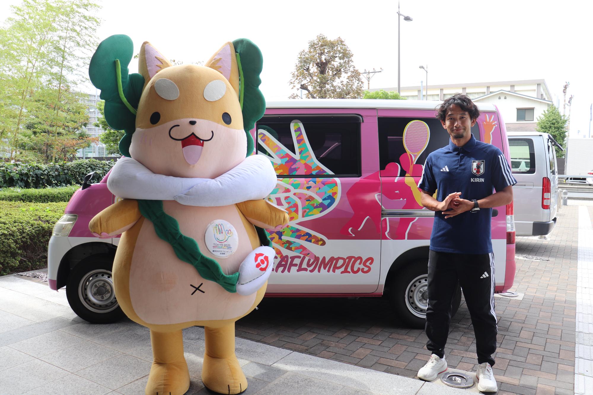 もり吉とデフリンピックサッカー選手である古島さんが専用のラッピング車の前に立っている