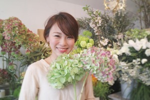 花屋さんの女性店員さんがきれいな2輪の花を持ち笑顔の写真