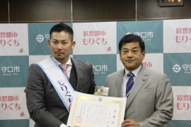 岩田稔さんと市長が二人で委嘱状を持って並んでいる記念写真