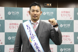 「もりぐち夢・未来大使」と書かれたタスキをかけた岩田稔さんがガッツポーズをしている写真