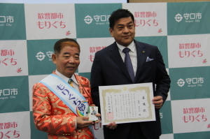 委嘱状を持った市長と池乃めだかさんが並んでいる写真