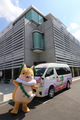 東部エリアコミュニティセンター前にコミュニティバスを停め、もり吉が記念撮影をしている写真