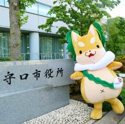 「守口市役所」と書かれた石銘板の横に立つもり吉の写真