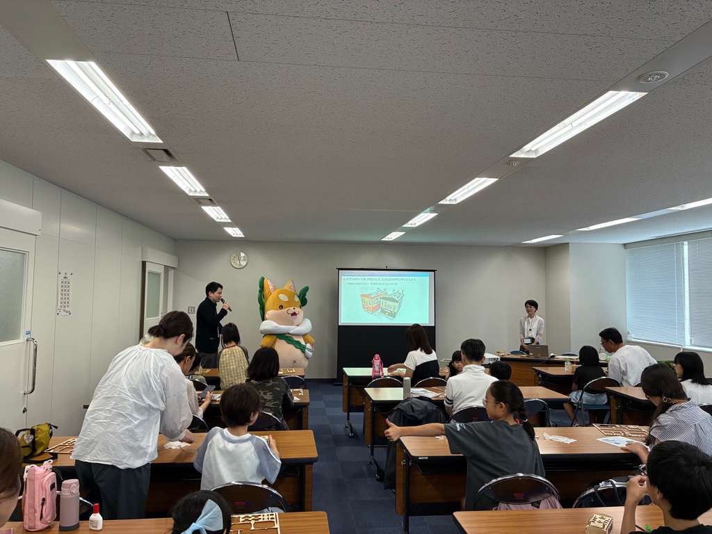 もり吉が教室の前で立っていて、左右に司会者がいる